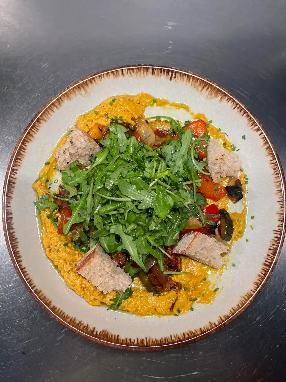 Hummus bowl with roasted vegetables, rocket, and sourdough croutons